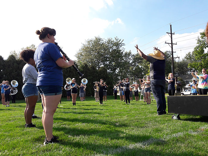 Band Director DaJuan Brooks conducting the band during a Marching Band rehearsal on a 90 degree day.