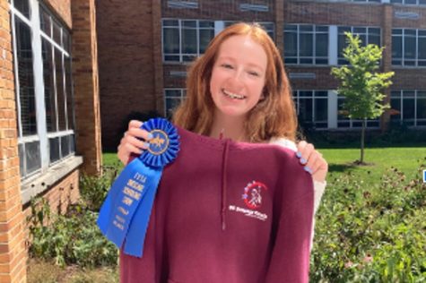 Senior Mia Cassin poses with the ribbon she won from a horseback riding competition with her horse  named Belle. 