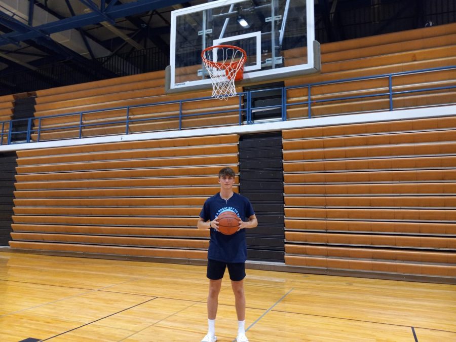 Varsity guard Justin Waterman stands holding a basketball on his home court at DGS.    