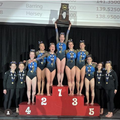 The girls gymnastics team cheers from the podium as they are crowned state champions.