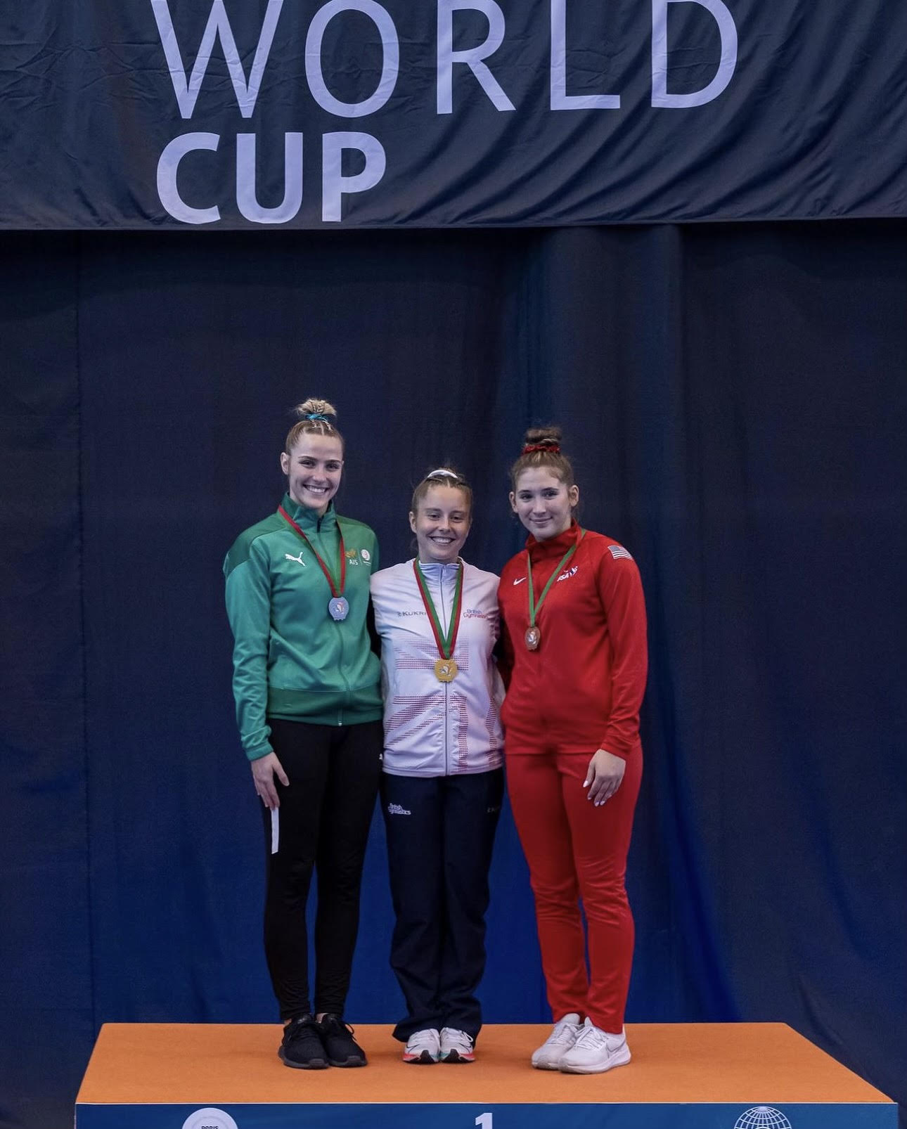 Kent stands with first and second place medalists Kristy Way (GBR) and Cheyanna Robinson (AUS) at the Trampoline World Cup in Coimbra, Portugal.