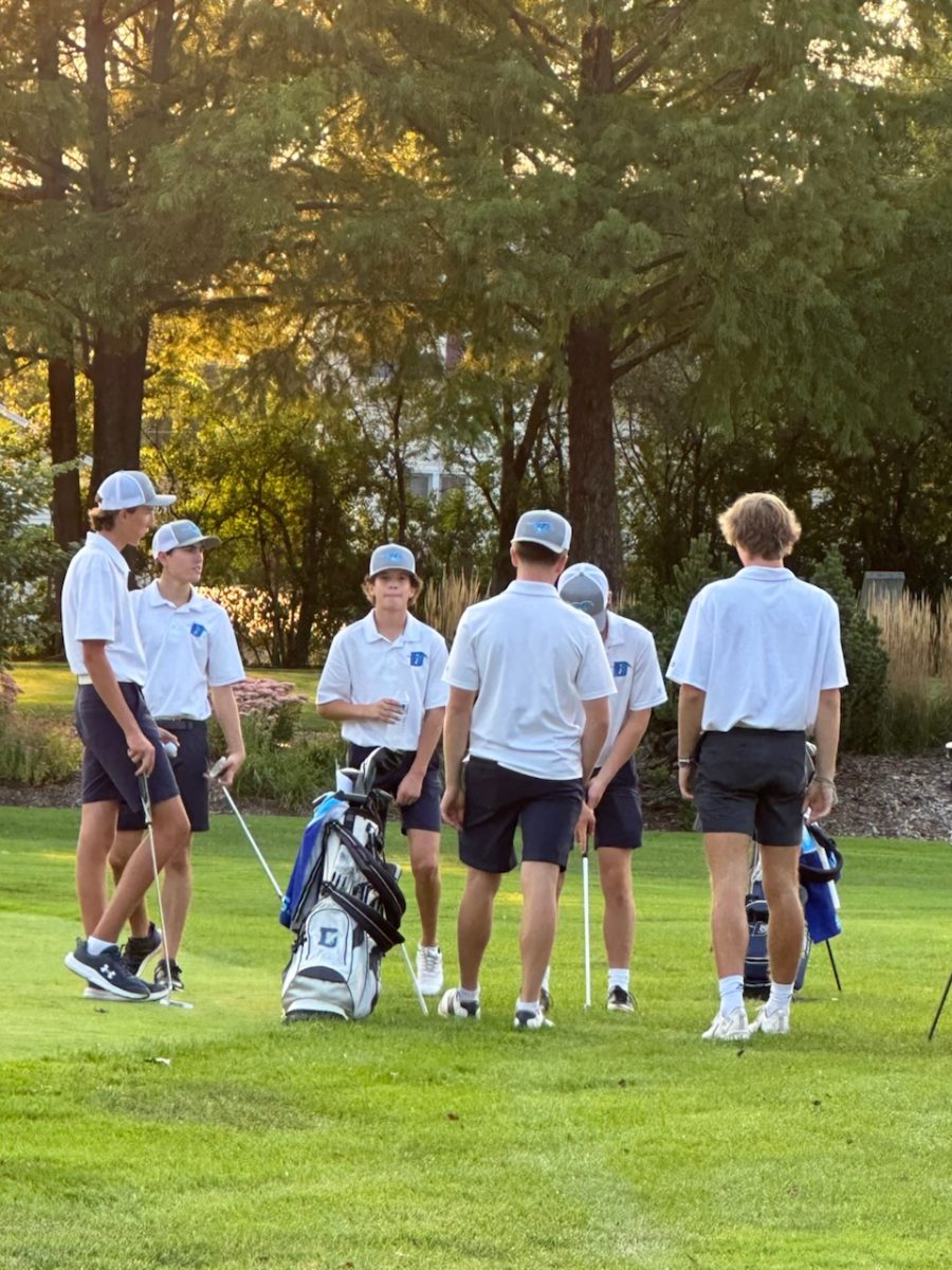 Gabe Garron and his fellow golf teammates meet together in between a hole during their tournament. 