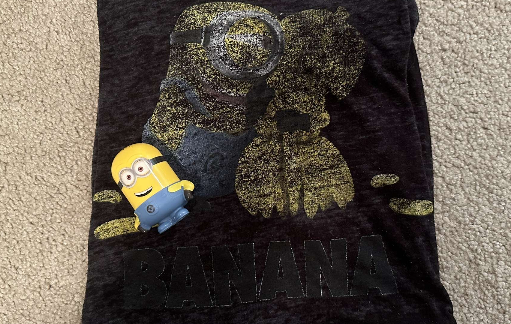 A worn Minion t-shirt lays by a trinket from   the same cinematic universe-showing the loyalty and love for the miniature beings.