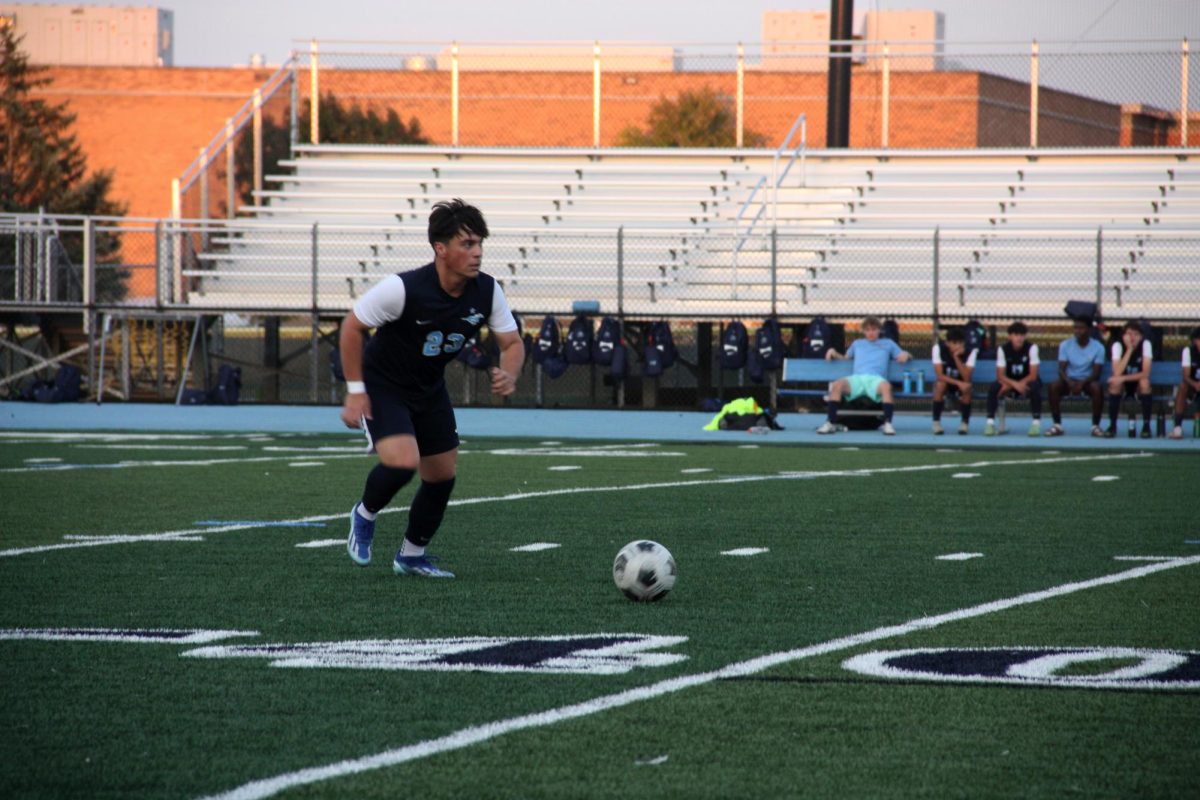 Senior Aleck Galvez dribbles the ball on the new turf field during a home game.