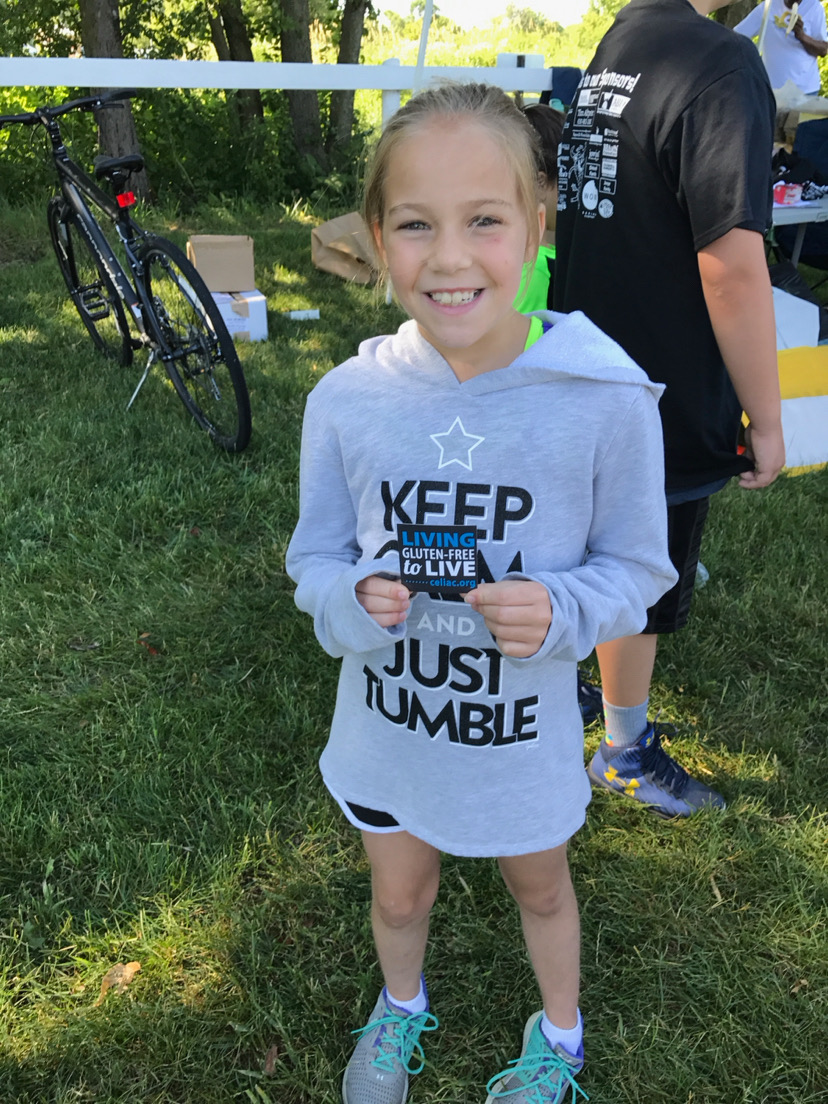 I've had Celiac Disease since 2011, and here is me at a walk in 2017 for Celiac Awareness, holding a sticker reading "Living gluten-free to live."