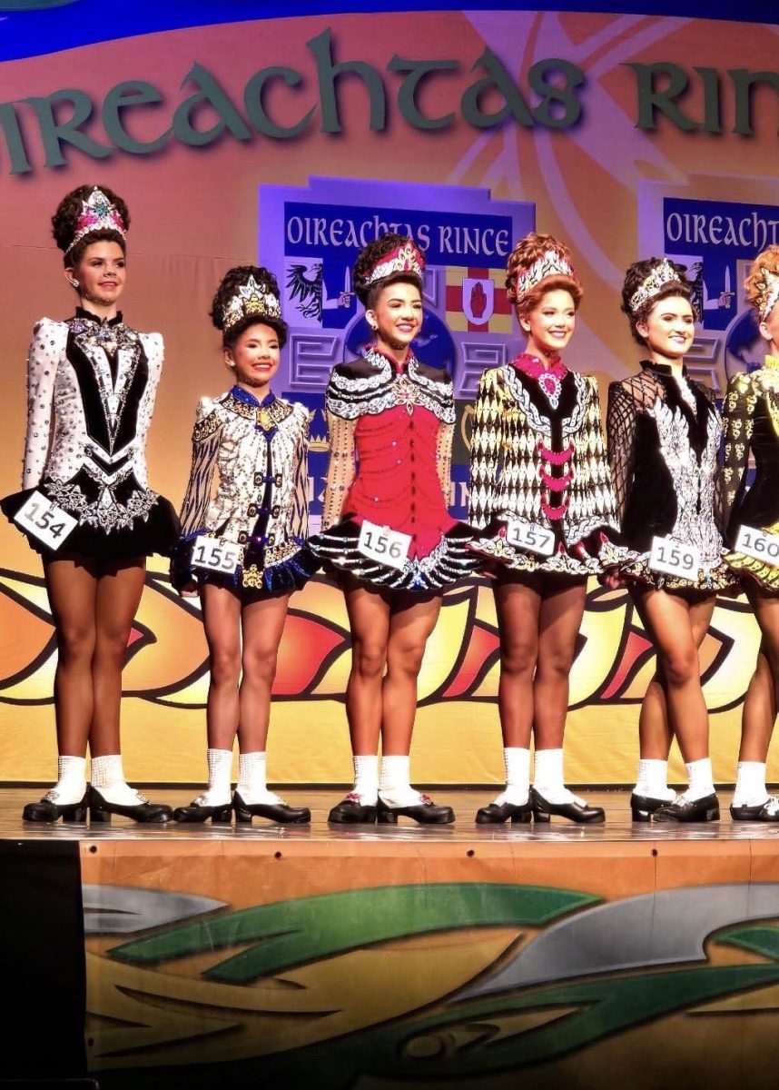 Irish dancers pose on stage, ready to compete their routines.