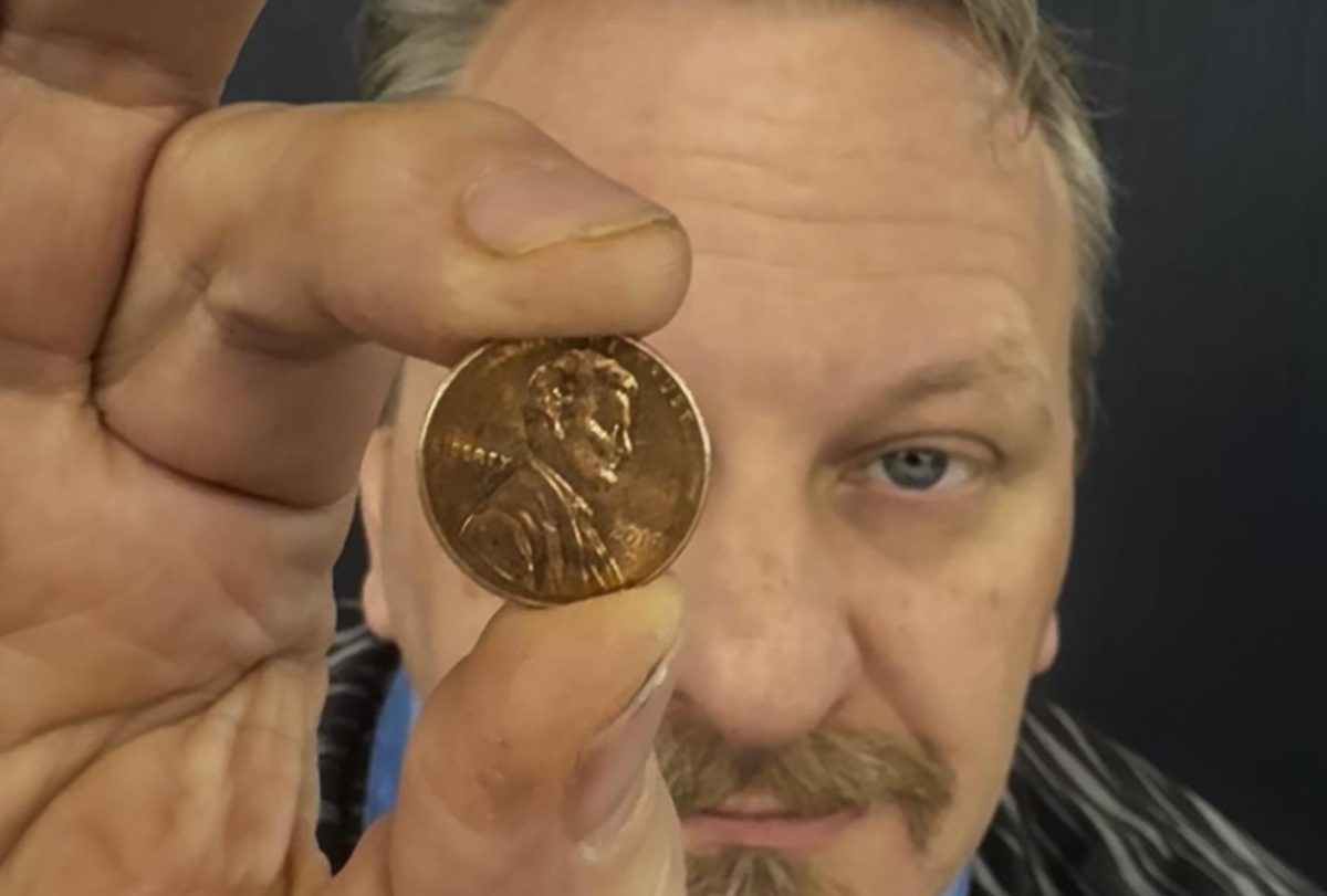 American history teacher James Chochole poses with the historic coin.